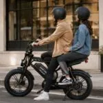Casal com capacetes em bicicleta elétrica preta com banco para garupa