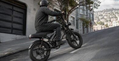 Bike elétrica preta subindo rua inclinada em cenário urbano