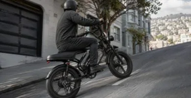 Bike elétrica preta subindo rua inclinada em cenário urbano