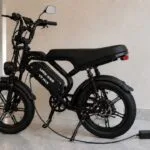 Bicicleta elétrica preta conectada ao carregador em garagem moderna