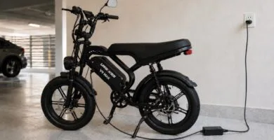 Bicicleta elétrica preta conectada ao carregador em garagem moderna